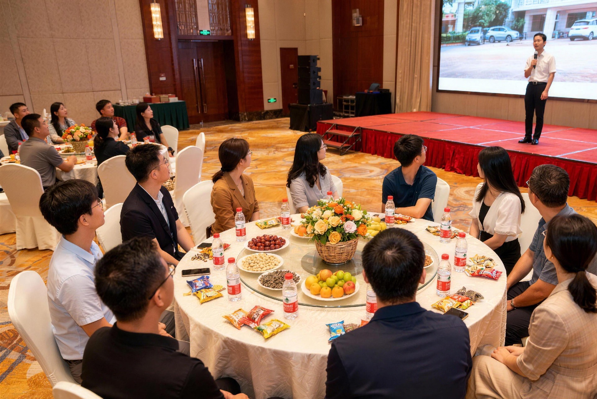 jimeng-2025-11-30-2014-13 个人围坐在一个酒店桌子边,男女都有,全景,桌子上有个装饰花篮,每个人的桌上..jpg